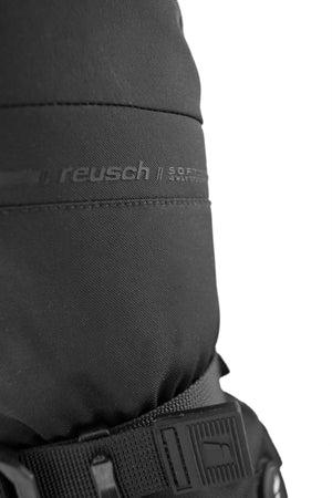 Close-up of the wrist strap securing the Reusch Advanced Heat R-TEX® XT Black Mitten on the wrist, with the logo design visible on the back side of the mitten.